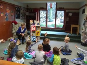 Ms. Sally reads to a room full of children.